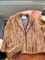 Front view of brown fur jacket showing label and lining
