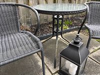 table, two chairs, lantern, tomato cage visible
