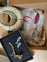 Box containing rattan wall pocket, pink glass swan, black presentation box with snuffer, and crystal candelabra parts