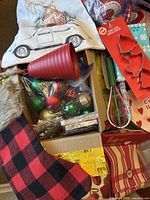 view of pillow cover, stocking, box of ornaments, red cup and related Christmas items