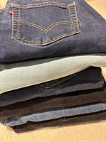 Stack of folded jeans showing Levi’s pocket stitching and red tab