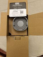 Opened carton showing gray vessel cap inside box