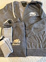 Hoodie, sweatpants and two pairs socks arranged on bed