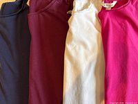 Four solid colour long-sleeve T-shirts laid out side by side