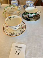 Five assorted English bone china teacup and saucer pairs on table