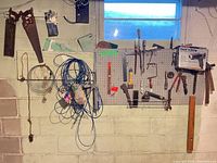 Overall wall view showing pegboard, boxed heat gun, hand saws, cables and various tools