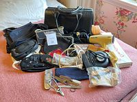 Overview of handbags, electronics, grooming tools on bed