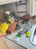 Overall view of assorted utensils, copper fish mold, cleaning items on counter