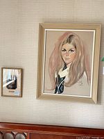 Wall view showing both framed pieces: large pastel portrait and smaller photographic print