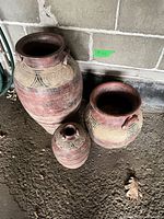 Three terracotta vases showing size variation and decorative motifs