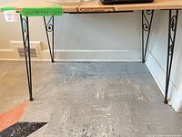 Full view of dining table showing laminate top and wrought iron scroll legs