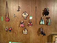 Wide shot of all ten hanging ethnic cloth dolls on wood panel