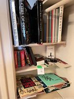 Shelf with large hardcovers, key finder box, ephemera and vintage clock radio visible