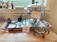 Lot overview showing chafing dish, warming tray, metal stands and glass bowl