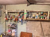 Overall view of wall shelf with assorted jars, paint cans, tools, cords