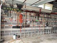 Overall view of tools, ladder, cord on garage wall