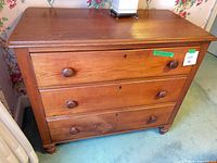 Full frontal view of dresser showing three drawers, knobs, feet and finish