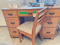 Front view of desk with chair tucked in, showing drawers and hardware