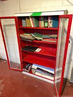 Full view of red and white glass-front cabinet with books on shelves