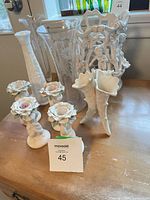 Group shot showing porcelain basket, candlesticks, cornucopia vases and etched glass vases on tabletop