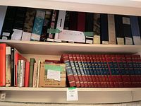 Shelf with World Book Encyclopedia volumes, misc books and box of cards