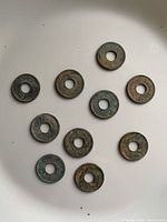 Ten tokens laid out showing both sides and patina