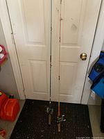 Both fishing rods standing against door showing full length and reels