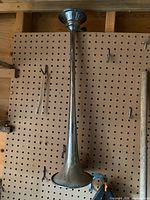 Full view of long chrome trumpet air horn hanging on pegboard