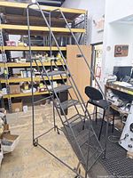 Full view of rolling warehouse ladder showing six steps, handrails and casters