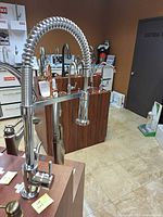 Full view of Aquabrass brushed nickel pull-down spring kitchen faucet mounted on display