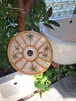 Full view of beige porcelain vessel sink with palm tree design and drain opening