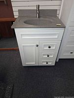 Front view of white vanity cabinet with integrated gray speckle sink and faucet