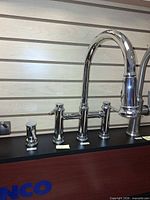 Front view of chrome bridge faucet and soap dispenser on display board