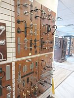 Three wooden showroom boards densely fitted with Bouvet door hardware—levers, knobs, backplates, hinges, pulls, latches—in assorted finishes