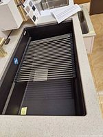 Top view of black granite composite Franke sink with roll-up drying rack placed across the bowl