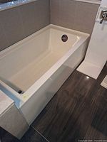 Full view of rectangular white acrylic bathtub in alcove