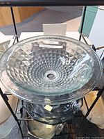 Top view of clear round glass sink showing faceted pattern and drain hole