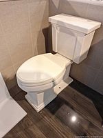 Full view of Kohler white two-piece elongated toilet installed on showroom floor