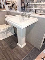 Overall view of Kohler white pedestal sink with chrome widespread faucet mounted beside toilet