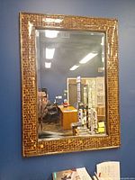Front view of rectangular wall mirror showing coconut shell mosaic frame and reflective glass