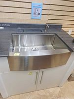 Full view of Moen stainless farmhouse sink installed in display cabinet