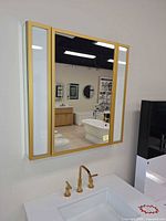 Front view of gold framed mirrored medicine cabinet mounted on wall above sink