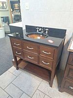 Full view of vanity cabinet with granite top, glass sink, faucet, backsplash