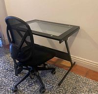 Desk angled side view showing Z-frame, mesh shelf, glass top