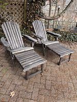 Pair of wooden Adirondack chairs with footrests extended