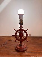 Full view of wooden ship’s wheel lamp with bulb installed