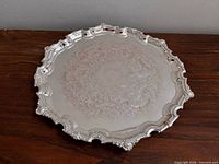 Top view of round silverplate tray showing chased center and scalloped rim
