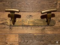 Front view of brass rack showing two cleats and embossed text