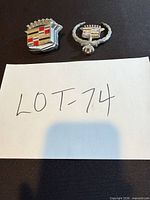 Both Cadillac emblems side by side on black surface