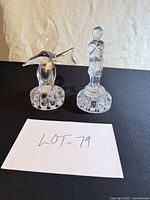 Overview of both clear glass figurines on black surface